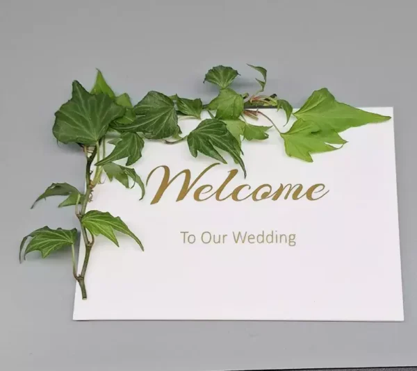 Bröllopsskylt med murgröna och texten Welcome to our wedding i guld.